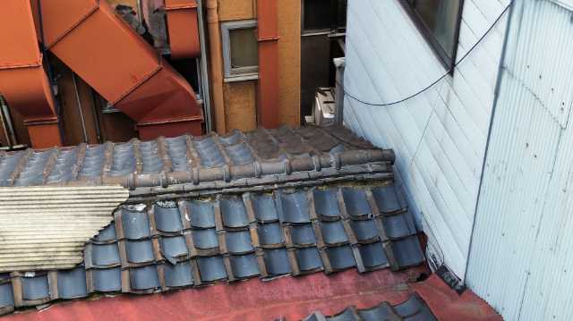 壁際で割れた瓦屋根
